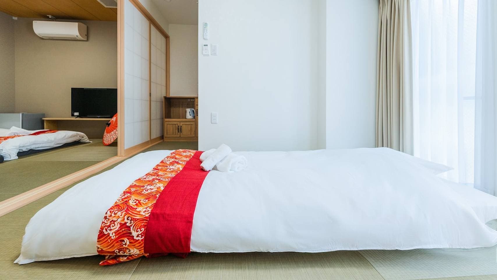 Japanese futon bedding on tatami mats in a bright apartment bedroom.
