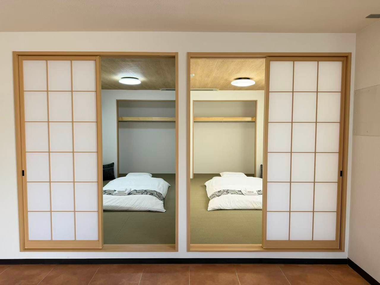 Japanese-style bedroom with futons on tatami mats visible through open shoji sliding doors.