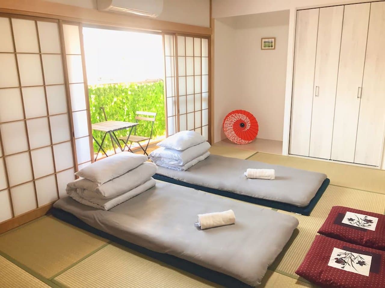 Japanese-style bedroom with two futons on tatami mats, shoji sliding doors, and a balcony.