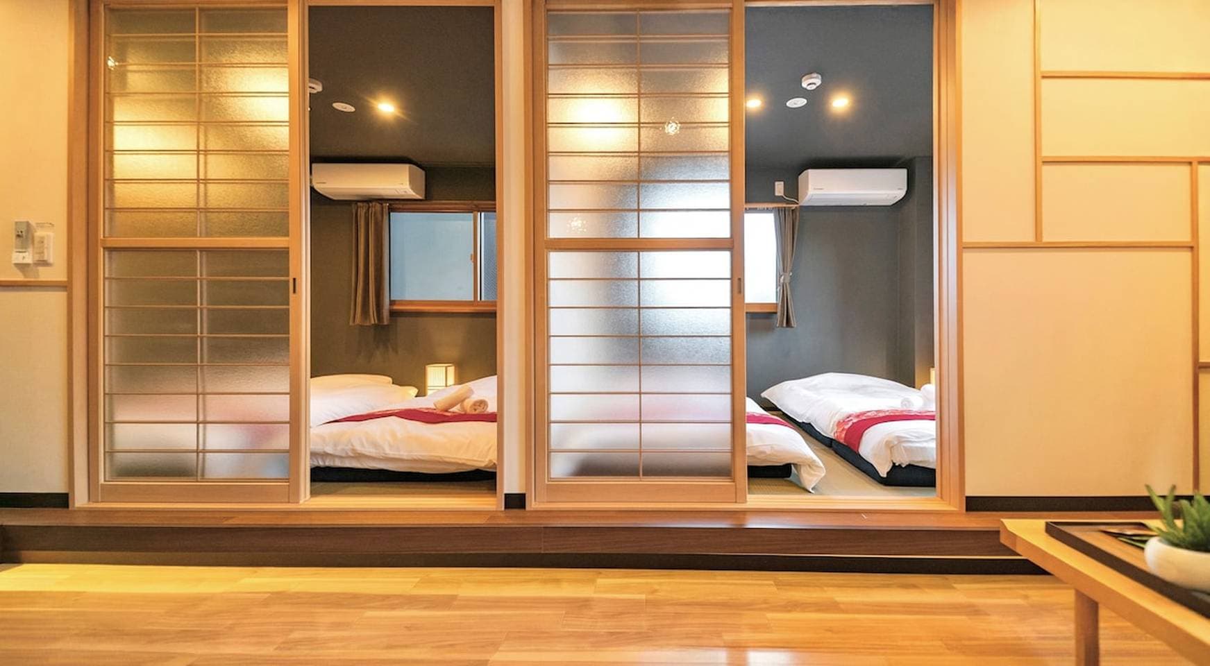 Japanese-style bedroom with futon beds seen through sliding wooden doors with frosted glass.