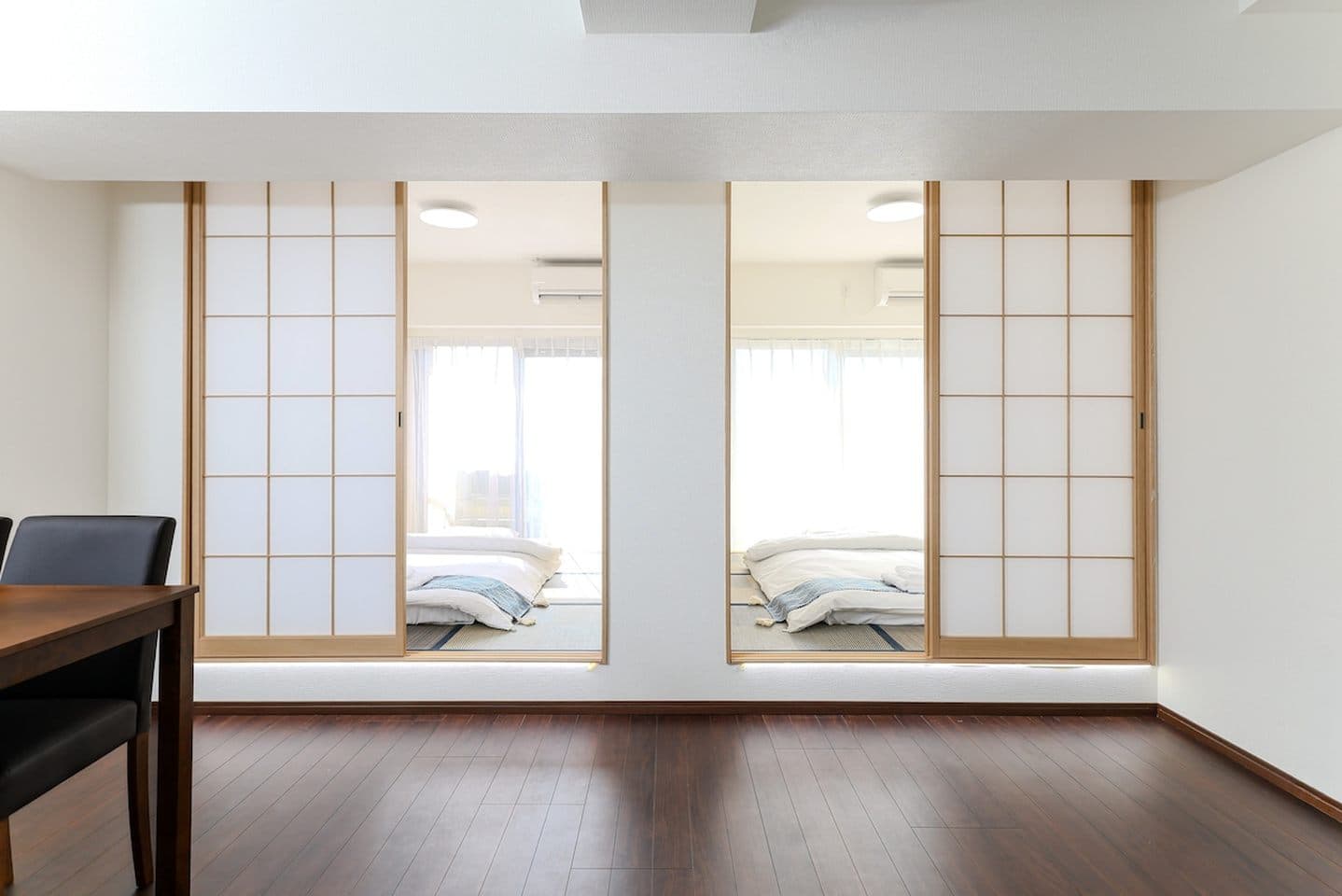 View through sliding shoji doors into a traditional tatami room with futon beds.